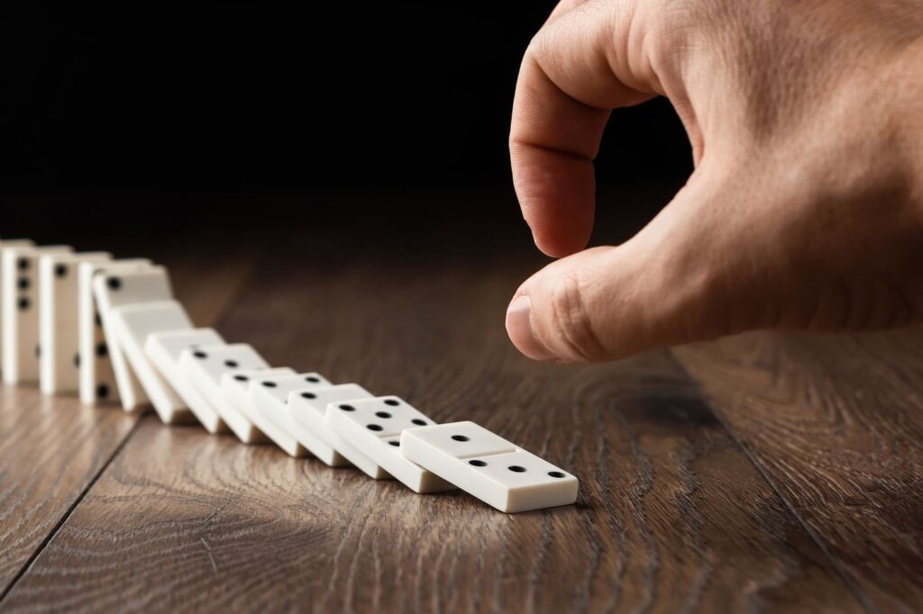 Fotografia conceitual do que são backlinks: uma mão iniciando uma reação em cadeia, simbolizando um voto de confiança.
