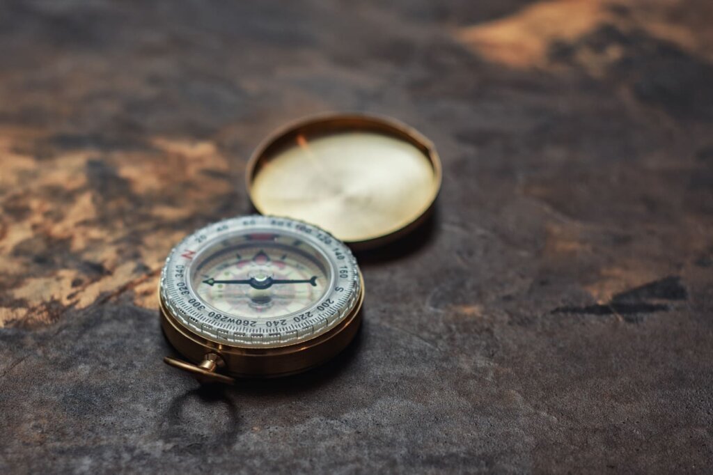 Estratégia holística de SEO: Bússola antiga apontando para um ponto luminoso, simbolizando a mudança de tática para qualidade
